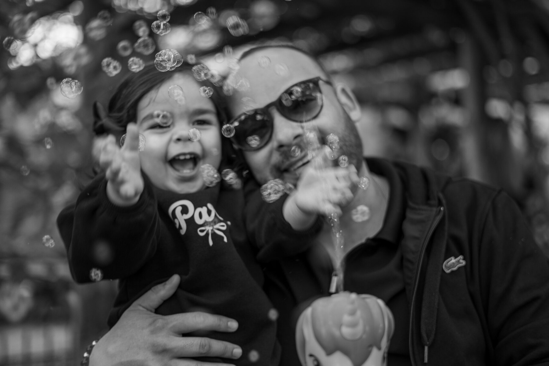 Padre e hija jugando con burbujas en blanco y negro
