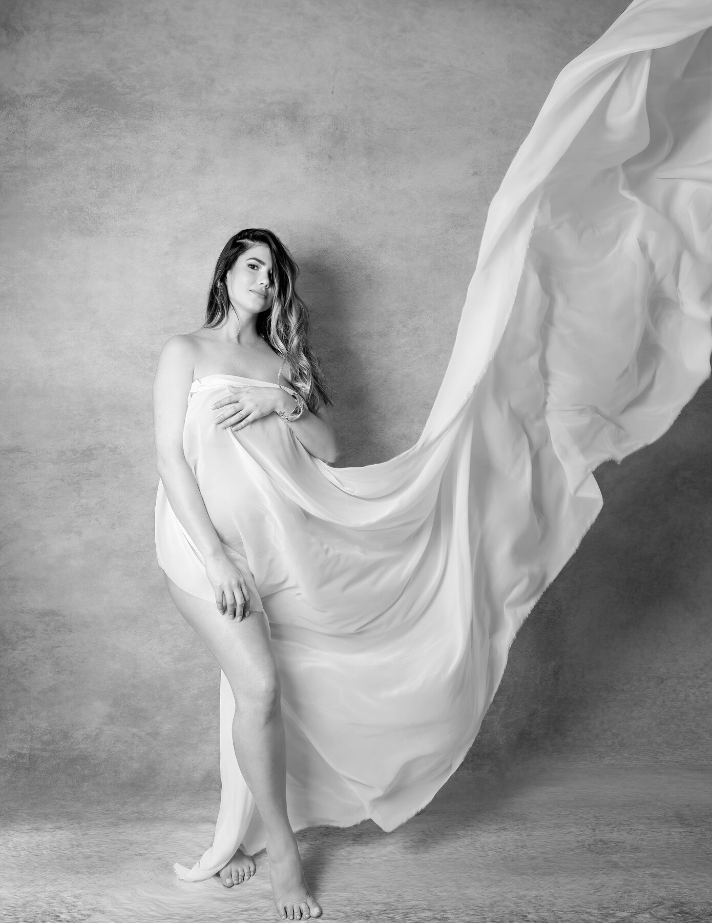 Retrato artístico de maternidad en blanco y negro con tela en movimiento